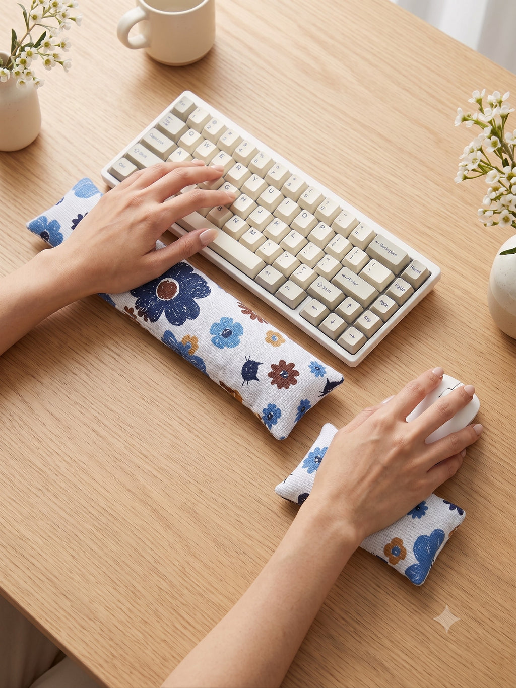Hands on a keyboard and mouse resting on the blue retro floral cat wrist rests