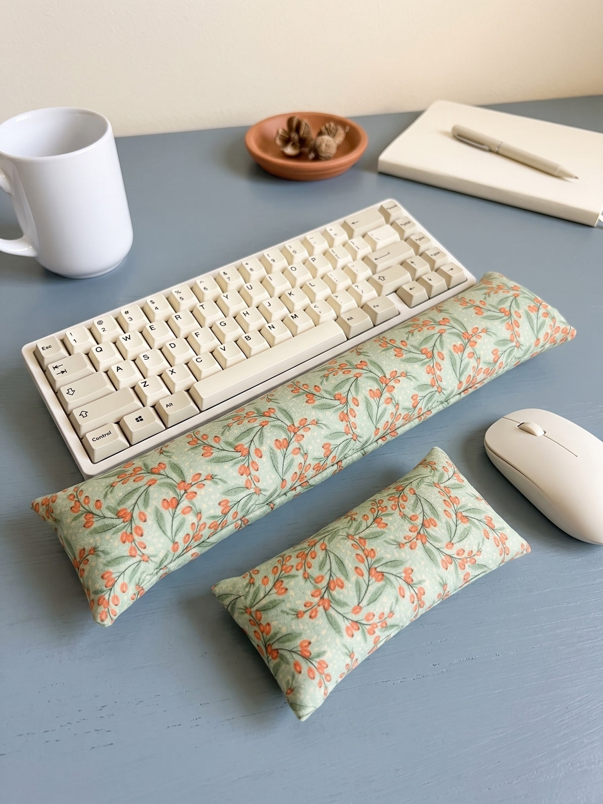 Sage berry keyboard and mouse wrist rests around a keyboard on a slate blue desk