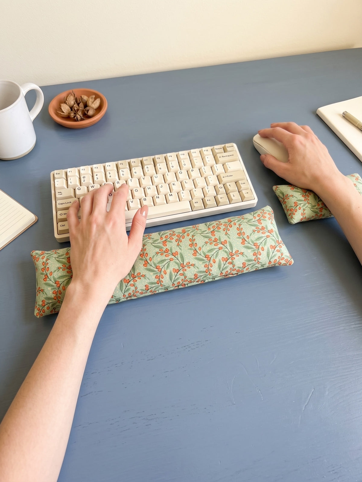 Hands on a keyboard and mouse resting on the sage berry wrist rests