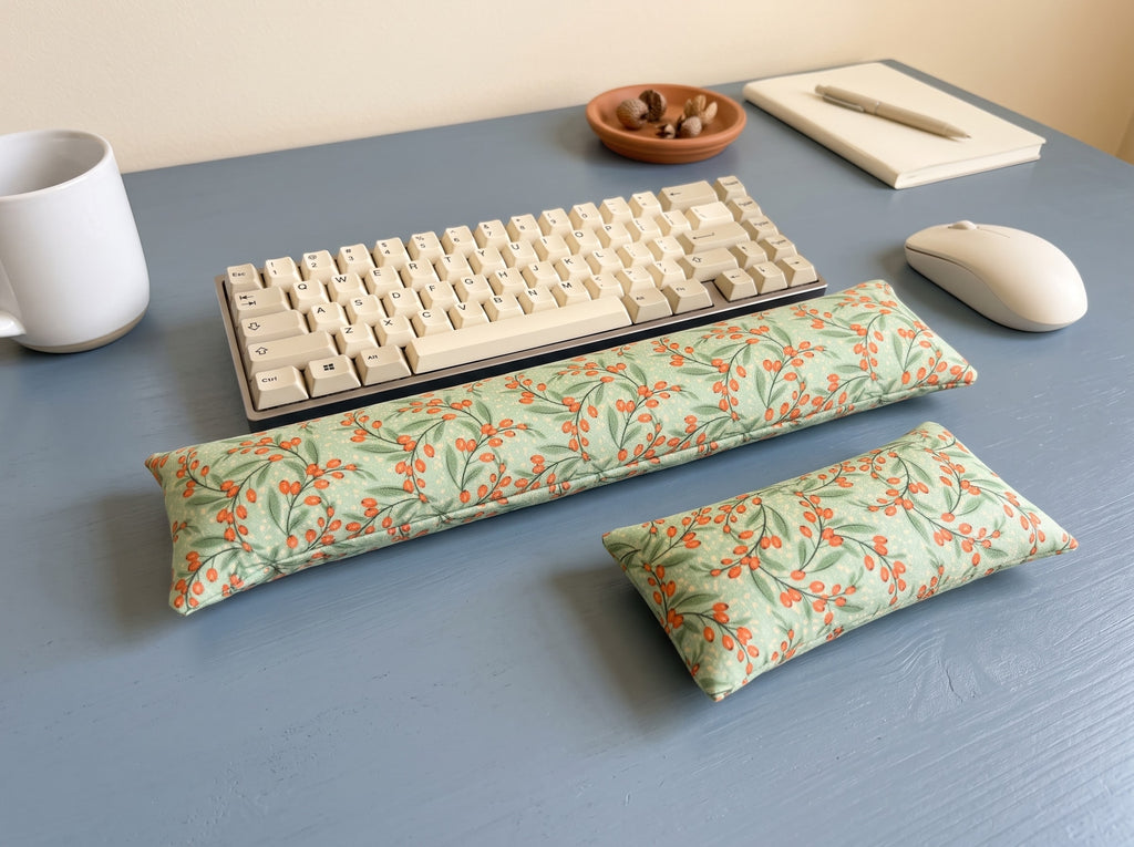 Sage berry wrist rest set in front of a keyboard on a slate blue desk