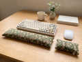 Sage floral corduroy keyboard and mouse wrist rests in front of a keyboard on a wooden desk