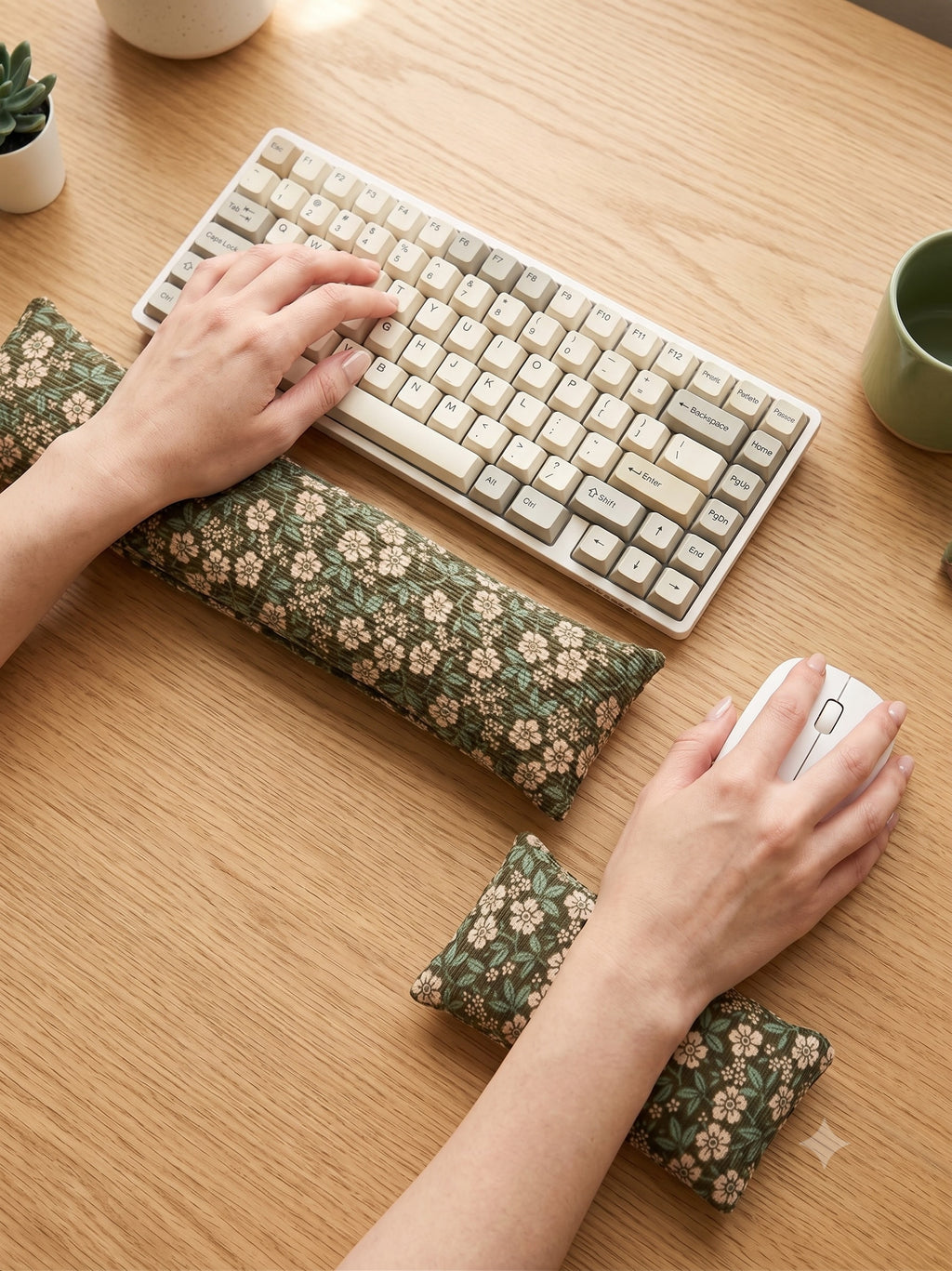 Hands on a keyboard and mouse resting on the sage floral corduroy wrist rests