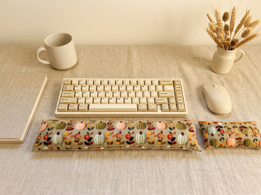 Sage pumpkin floral wrist rest set in front of a keyboard on a linen-covered desk