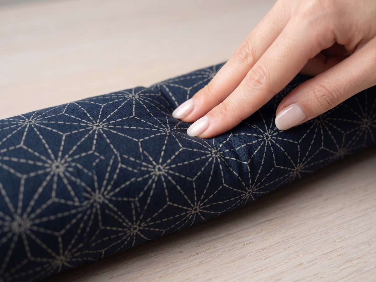 Hand pressing into the indigo sashiko wrist rest to show the buckwheat filling