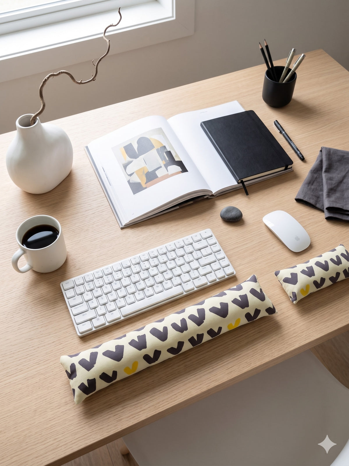 Scandi abstract keyboard and mouse wrist rests below a keyboard on a minimal desk with an art book
