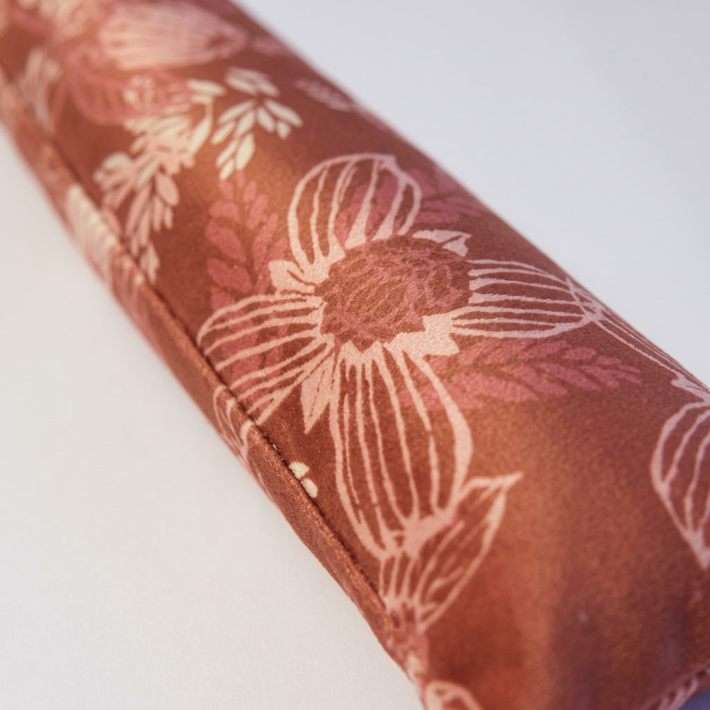 Close-up of blush botanical line art on soft terracotta velvet