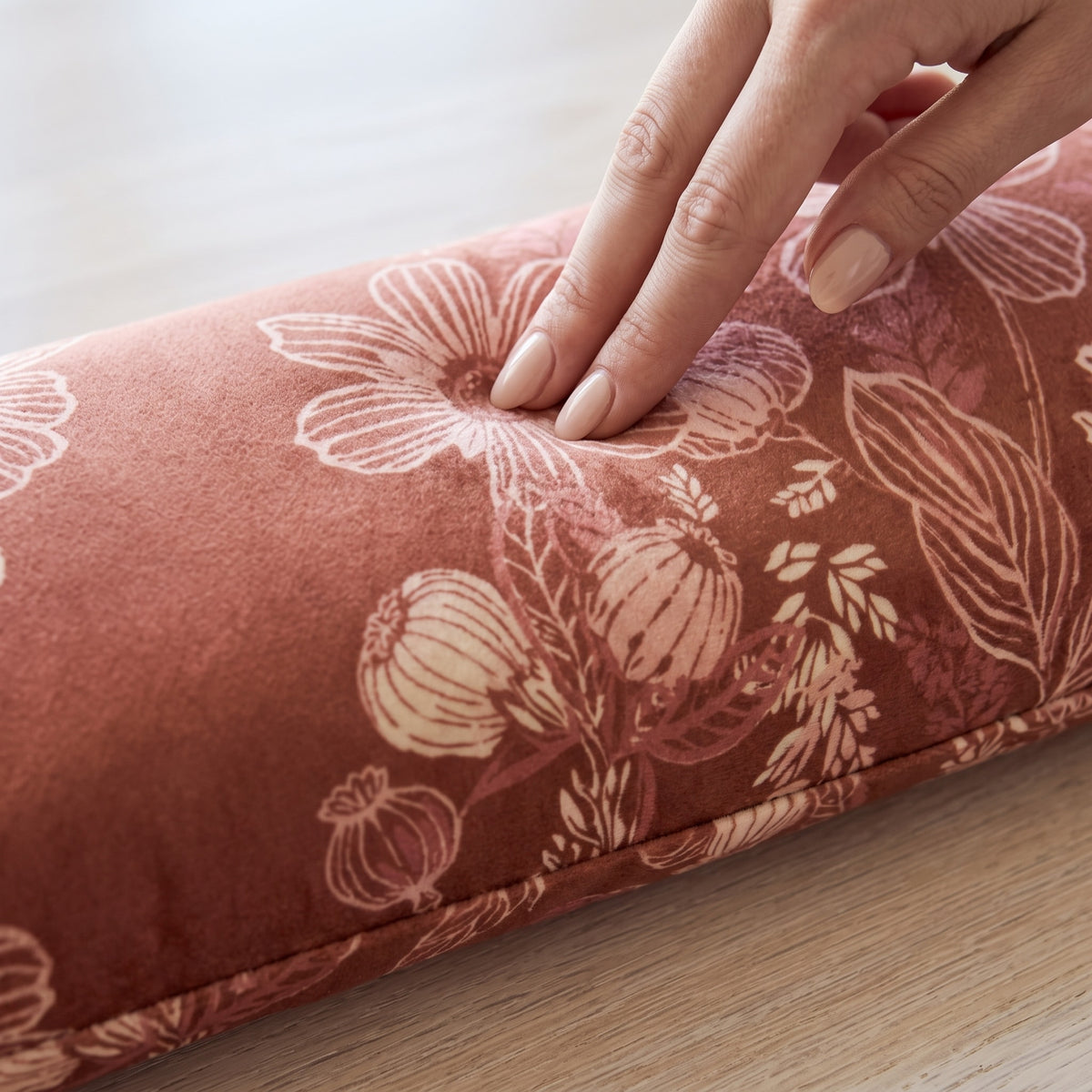 Fingers pressing into the terracotta velvet wrist rest to show the buckwheat filling