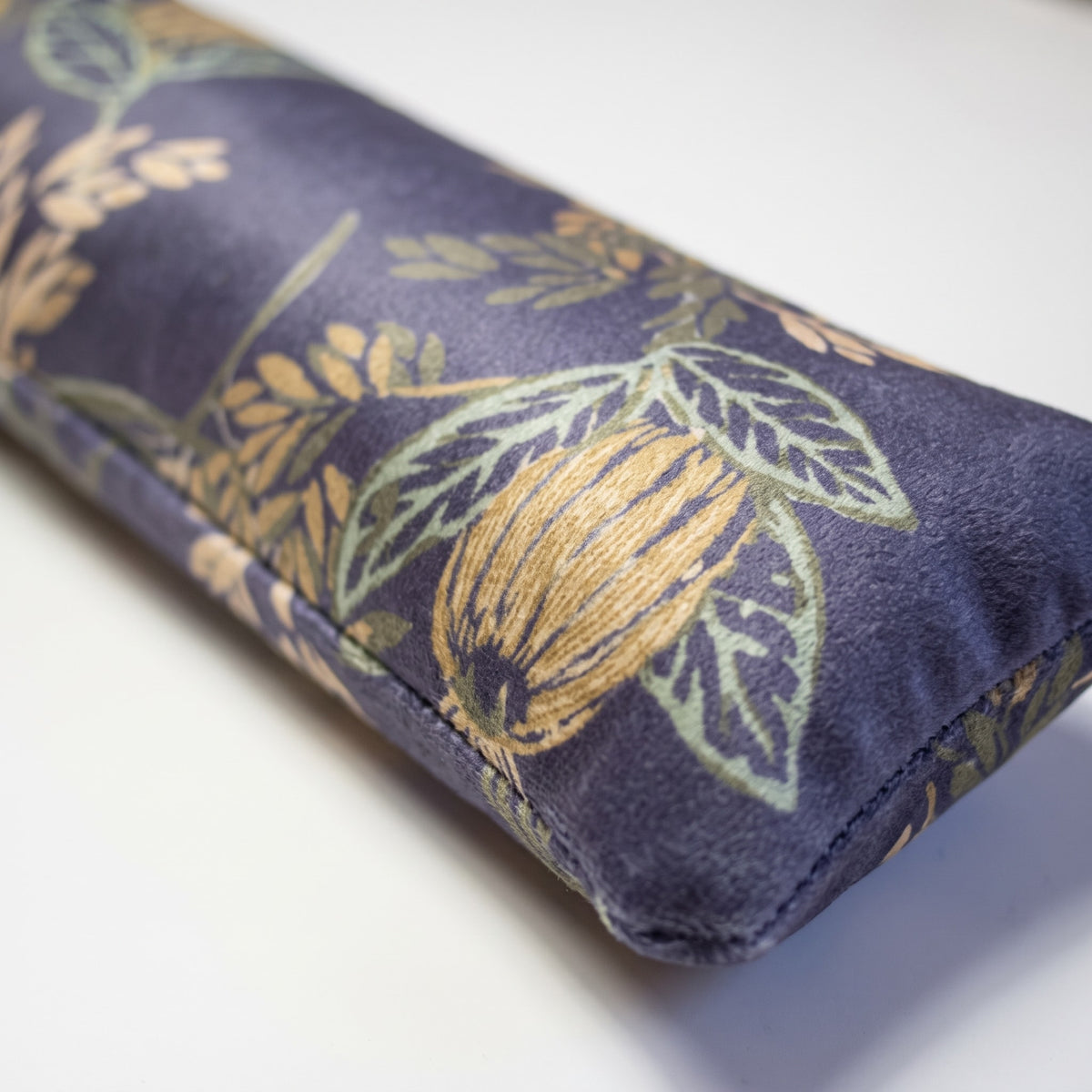Close-up of gold and sage botanicals on dusky blue velvet