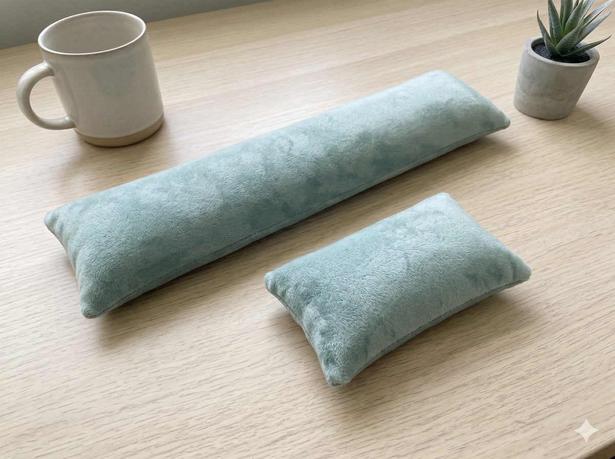 Sage green velvet keyboard and mouse wrist rests on a wooden desk