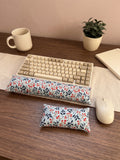 Winterberry keyboard and mouse wrist rests in front of a keyboard on a wooden desk with a mug and plant