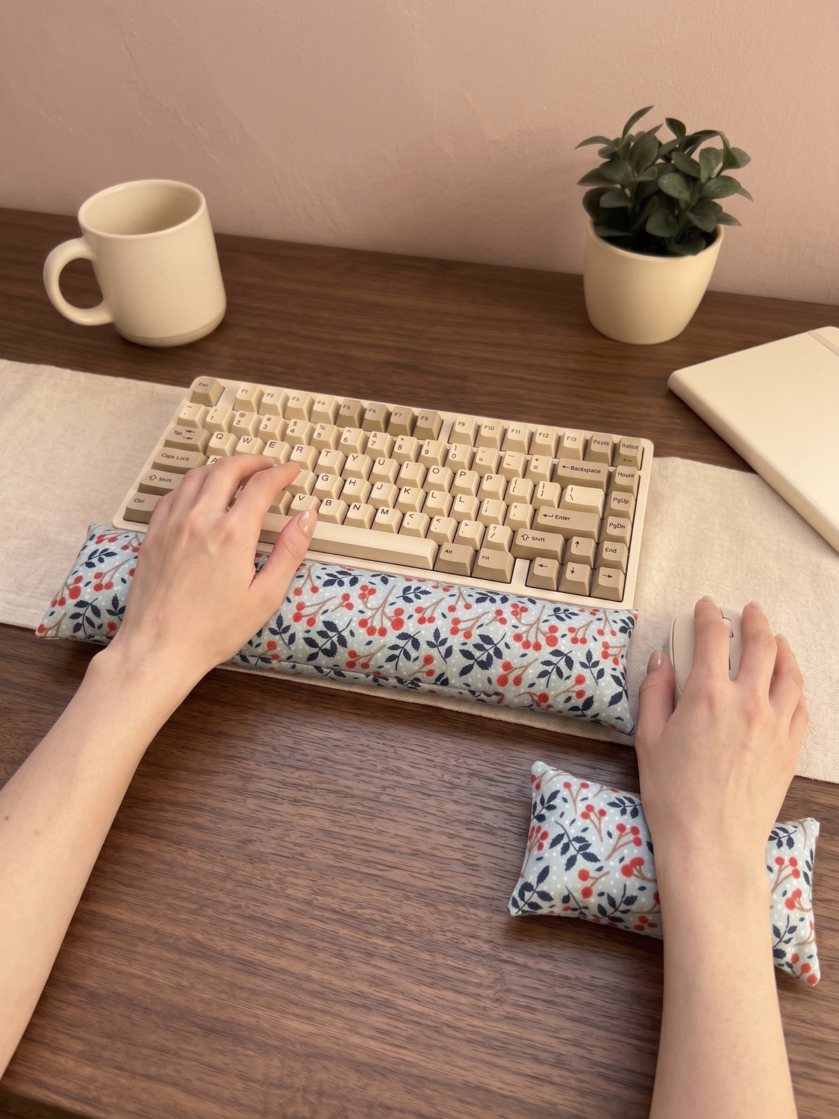 Hands on a keyboard and mouse resting on the winterberry wrist rests