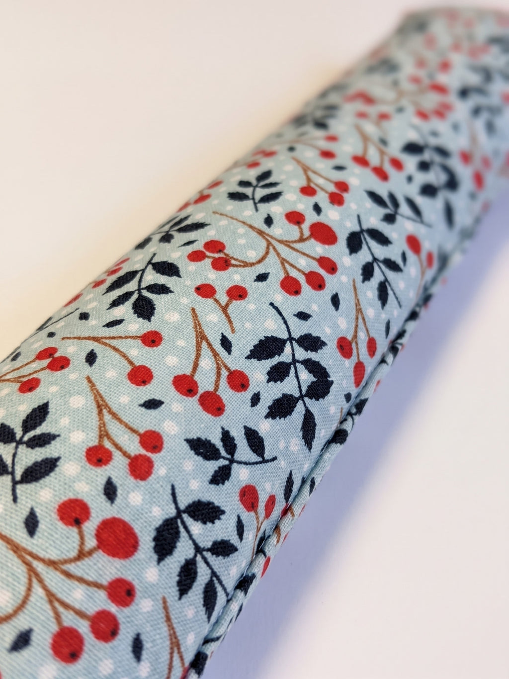 Close-up of red winterberries and navy leaves on ice blue cotton